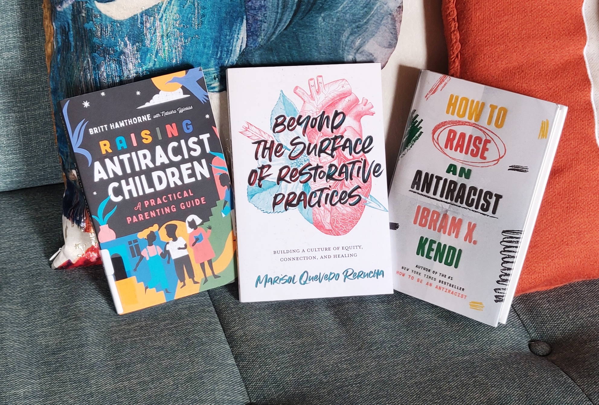 Image of three books on my couch: "Raising Antiracist Children: A Practical Parenting Guide" (Hawthorne & Yglesias), "How to Raise an Antiracist" (Kendi), and "Beyond the Surface of Restorative Practices: Building a Culture of Equity, Connection, and Healing" (Rerucha).